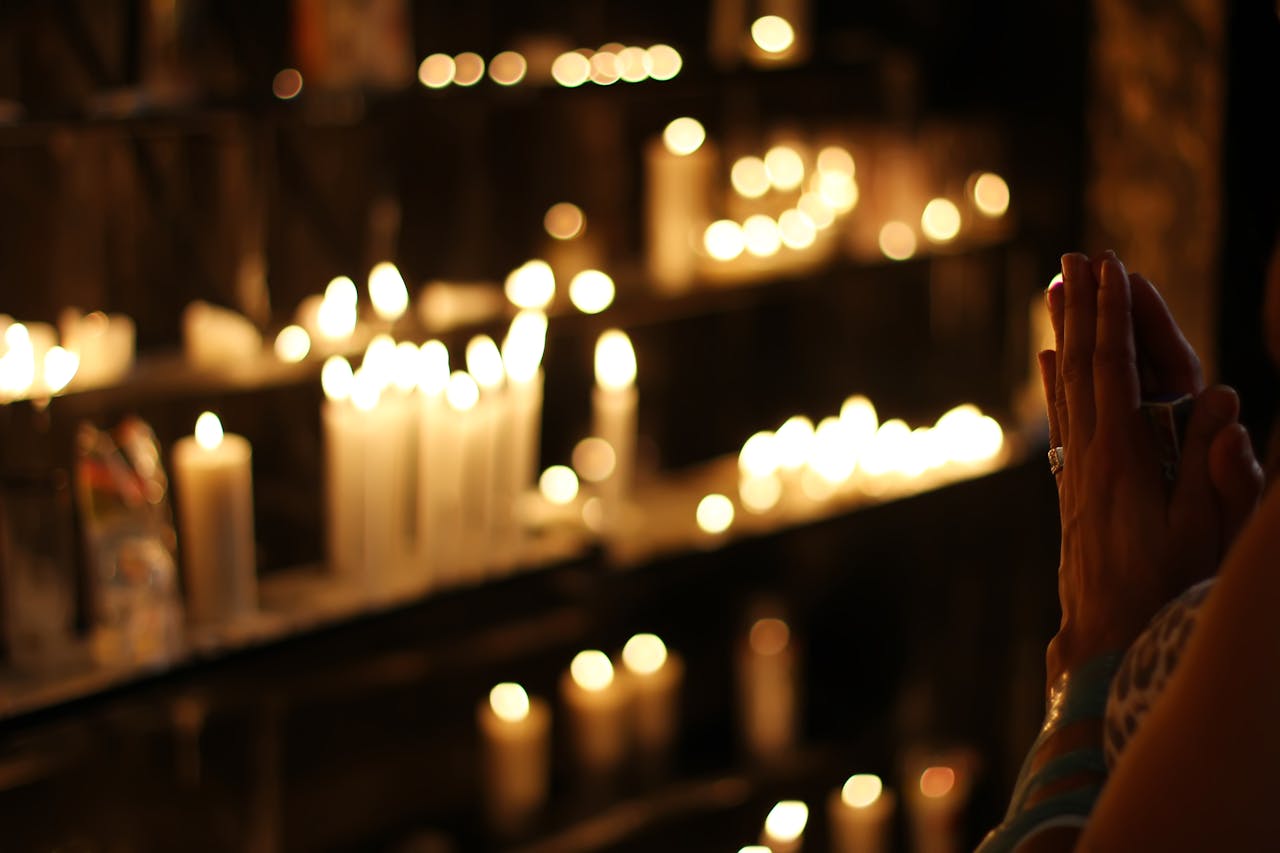 Hands clasped in prayer by candlelight in a church in São Paulo, Brazil, evoking a spiritual atmosphere.