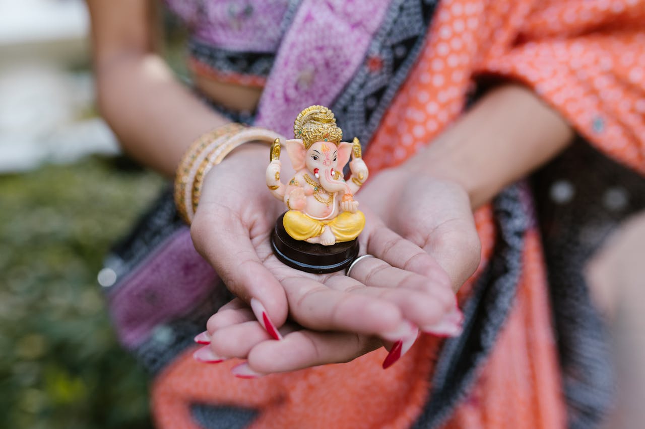 A woman's hands holding a Ganesha figurine, symbolizing Hindu spirituality and culture.